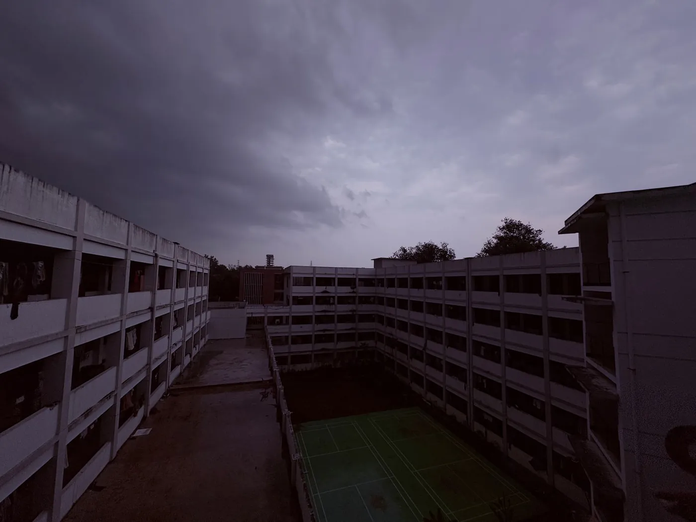 A dormitory courtyard and sports court under heavy storm clouds